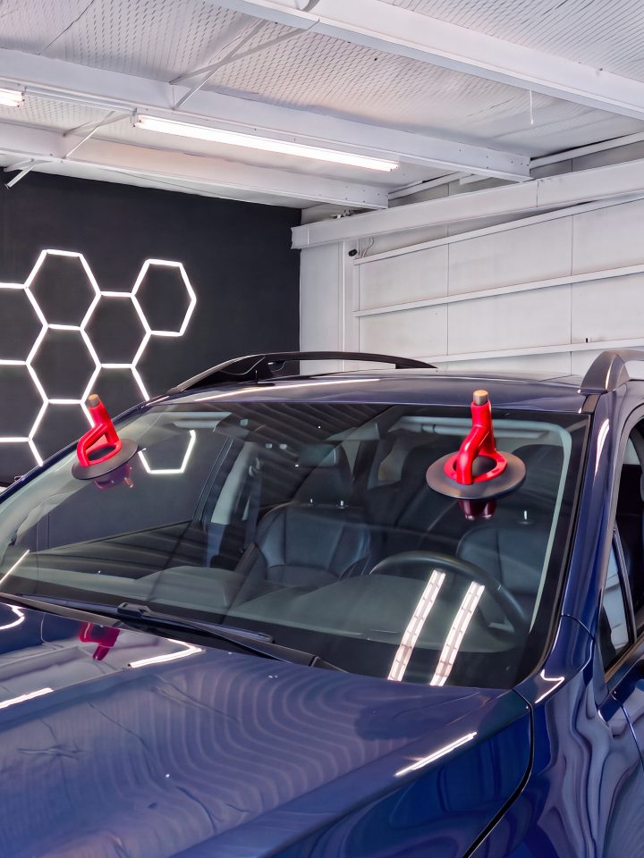 Two red suction cups set on the windshield of a dark blue car in the bay